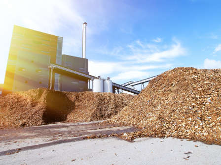 bio power plant with storage of wooden fuel against blue sky