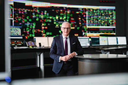 APG-Vorstand Gerhard Christiner in der APG Power Grid Control vor großen Bildschirmen mit Stromdaten.