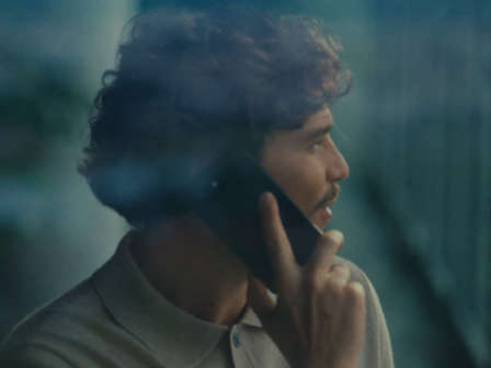 Mann telefoniert am Handy und sieht dabei aus dem Fenster.