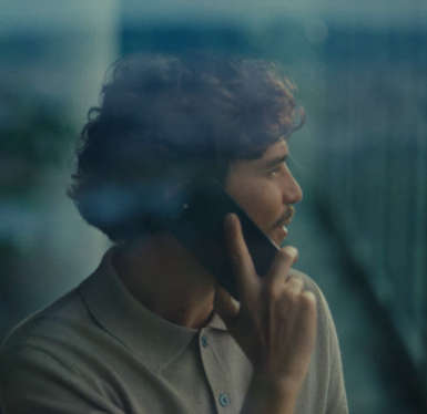 Mann telefoniert am Handy und sieht dabei aus dem Fenster.