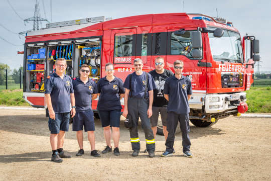 Sechs Feuerwehrmänner- und frauen vor einem Feuerwehrauto beim Tag der offenen Türe im Umspannwerk Zaya mit Blick in die Kamera.