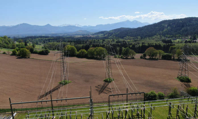 Zwei parallel verlaufende Stromleitungen über einem Feld