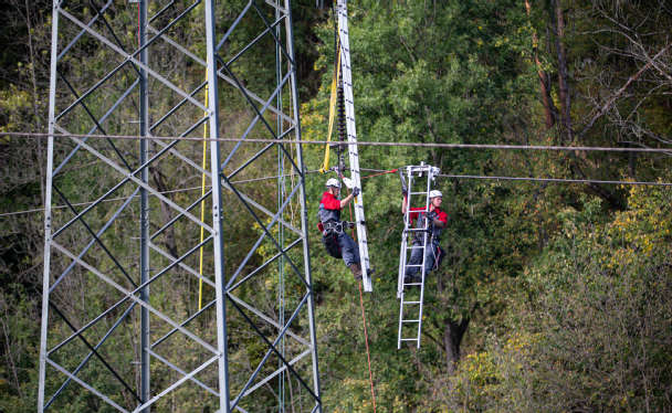 Zwei Leitungsmonteure auf einem Strommast.