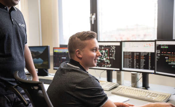 Zwei APG-Lehrlinge mit Blick auf Bildschirme.