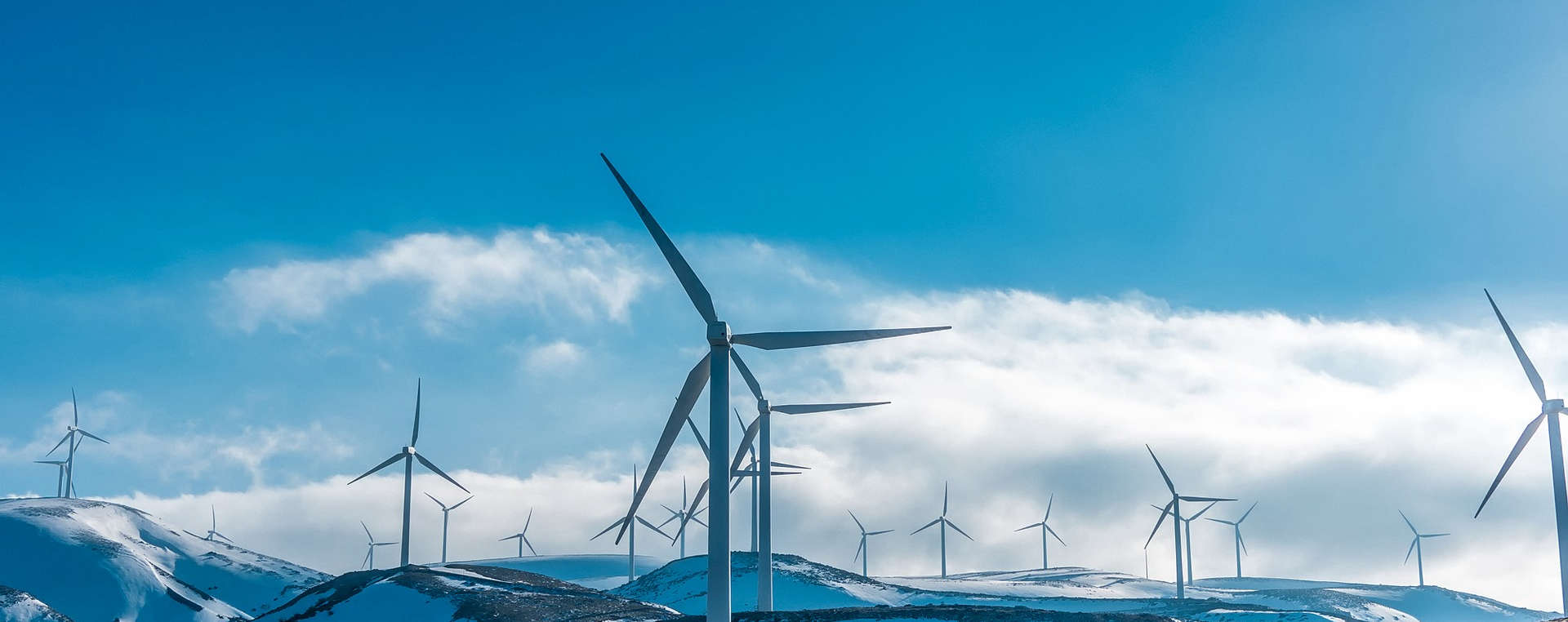 Eine größere Windkraftanlage auf schneebedeckten Berghügeln
