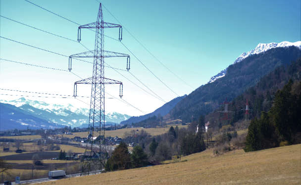 Ein Strommast im Vordergrund und im Hintergrund ein schneebedeckter Berg