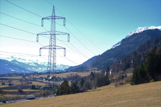 Ein Strommast im Vordergrund und im Hintergrund ein schneebedeckter Berg
